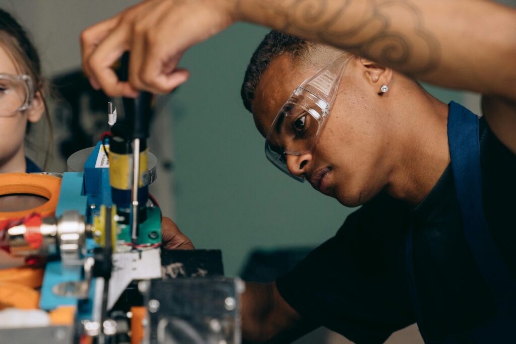 Two young technicians focus on electronic equipment assembly in a workshop setting.