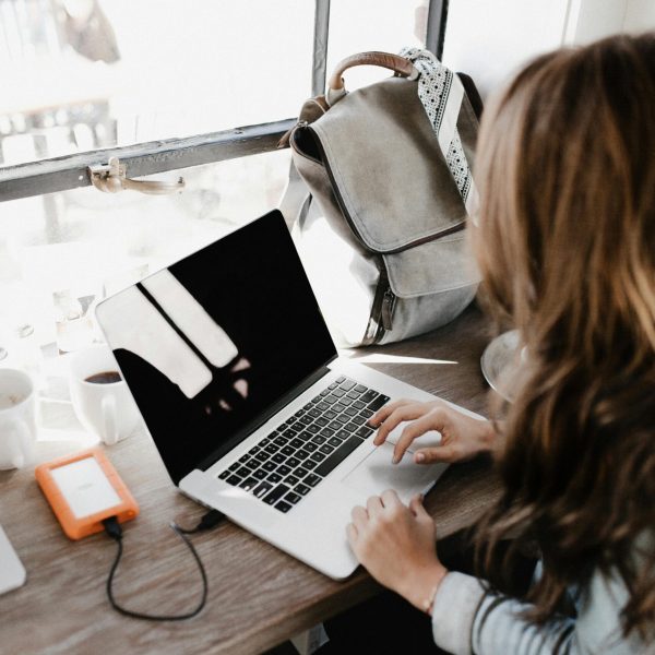 pexels-photo-3178818-3178818 A young woman works remotely at a café, using her laptop and external hard drive.